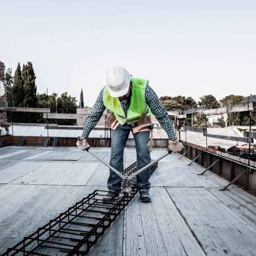 A mason cuts a metal structure with shears in a building under construction.